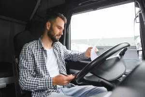 A truck driver is sitting in his cab checking over tax and accounting paperwork