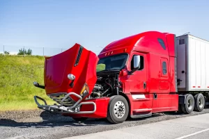 A red truck is parked on the side of the road with the bonnet open because it's broken down and needs repair