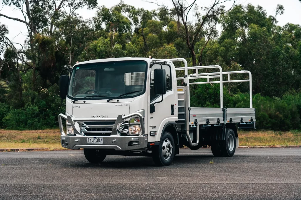 A parked 2024 Isuzu N Series Light Truck sitting on bitumen with the bush in the background.